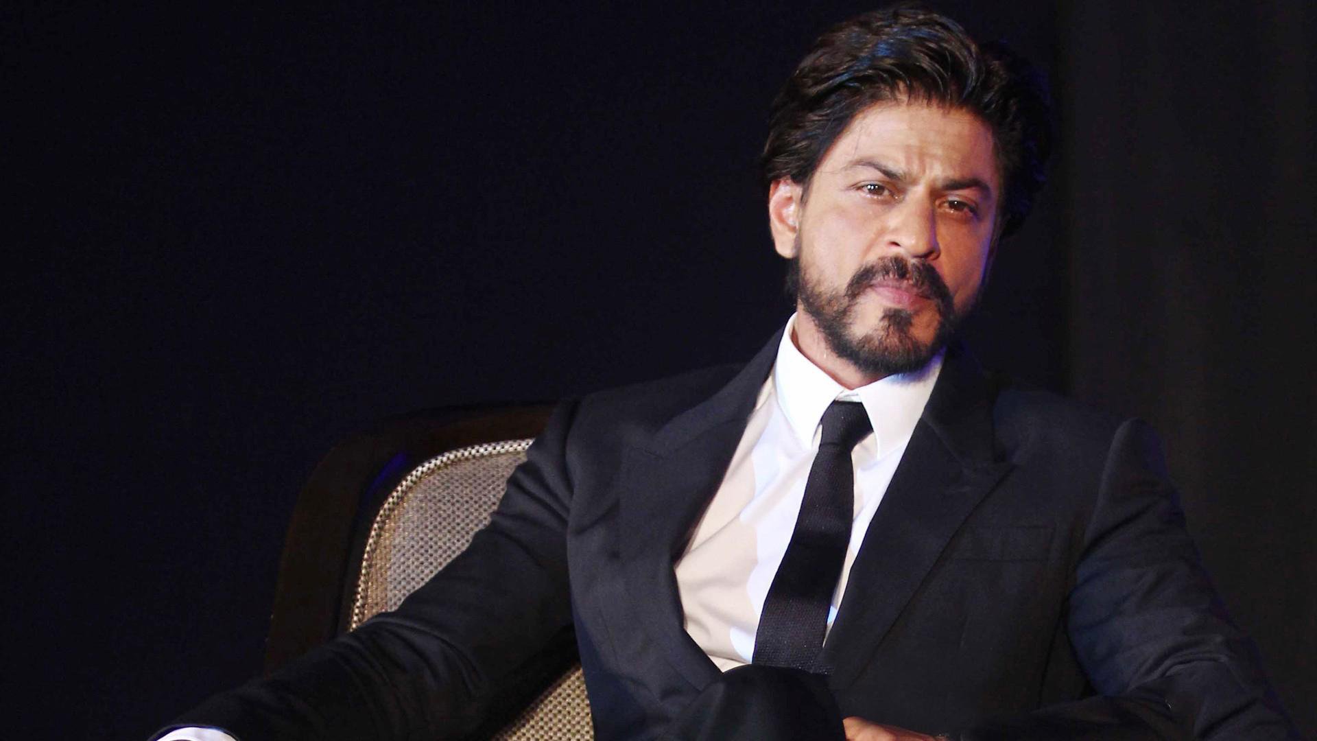 Shahrukh Khan duduk dalam setelan hitam